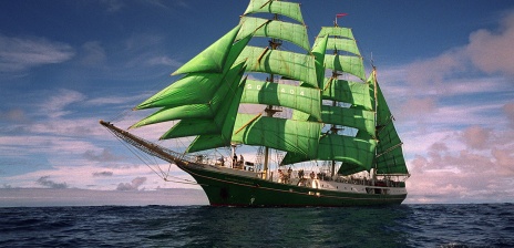 Ein Schiff mit grünen Segeln fährt über das offene Meer.